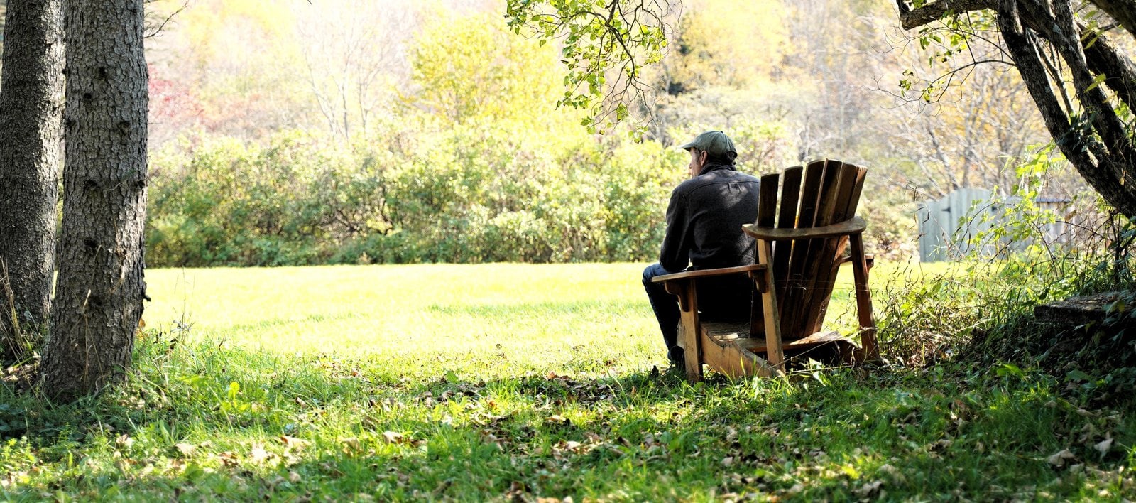 Someone in an Adirondack chair at the edge of the meadow